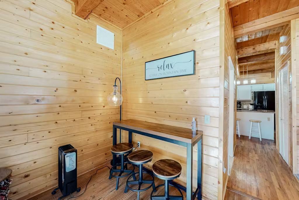 L’intérieur d’un chalet en bois comprend un bar, des tabourets, un luminaire et un panneau sur lequel on peut lire : « Détendez-vous ».