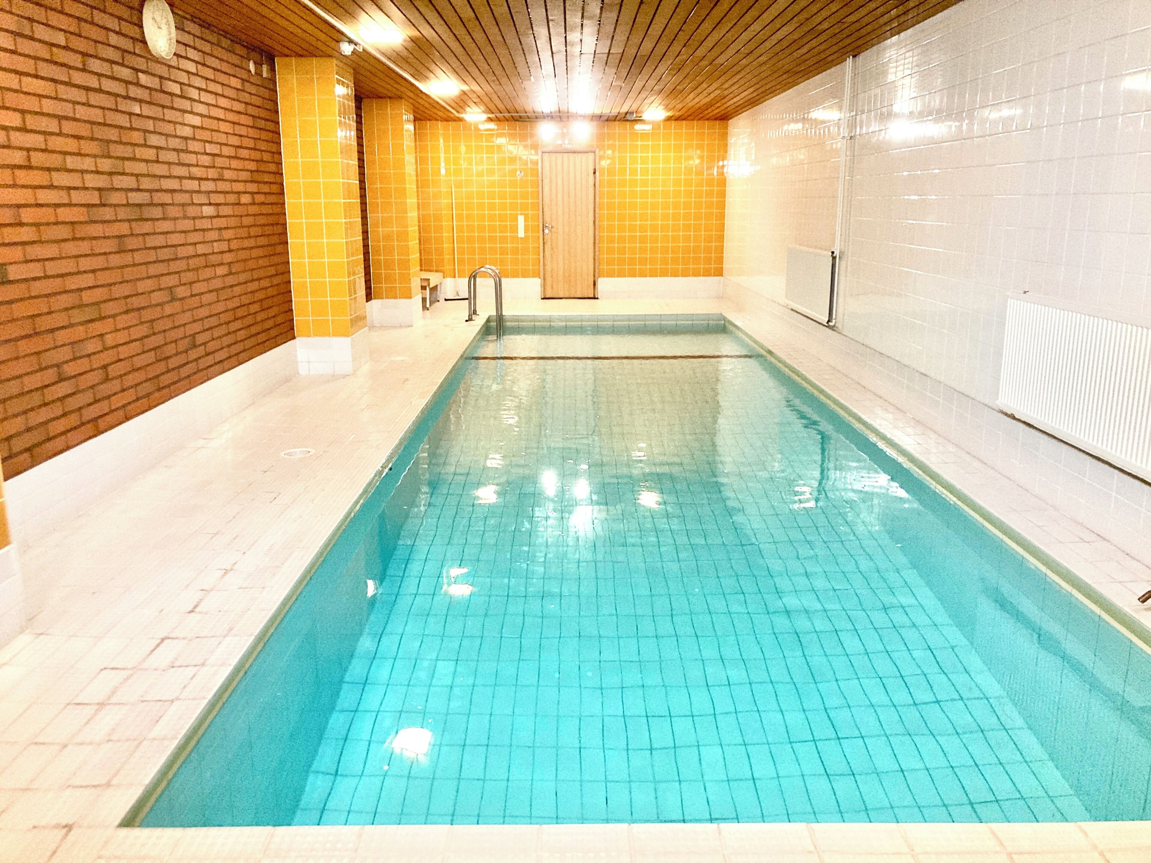 A swimming pool with tiled walls and a wooden ceiling.