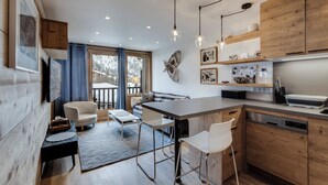 Une cuisine moderne avec des meubles en bois, un coin repas comprenant un canapé et des chaises, et une vue sur un paysage enneigé par de grandes fenêtres.