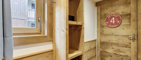 A wooden interior with a window, a door with a number plaque, and a shelf unit.