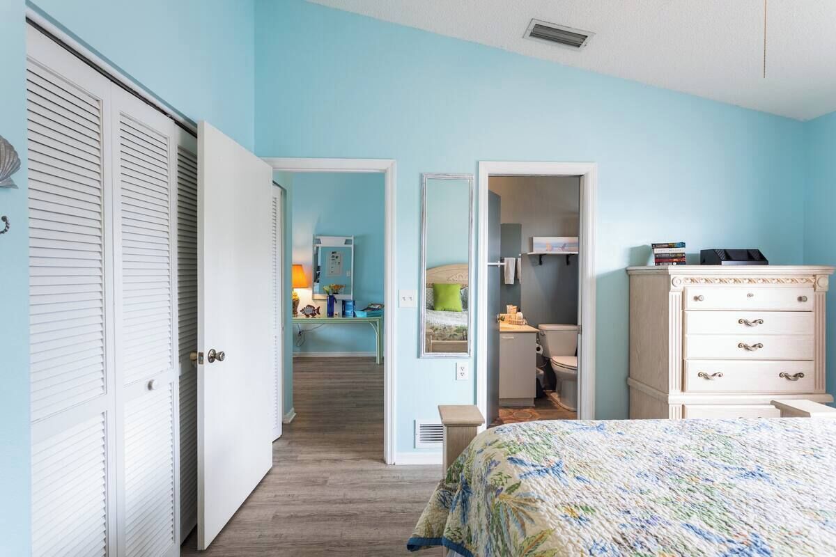 Un dormitorio con cama, cómoda y armario. Hay un pasillo que conduce a un baño.