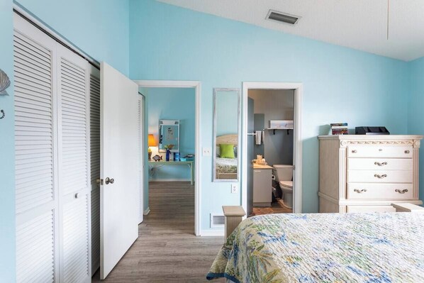 A bedroom with a bed, a dresser, and a closet. There is a hallway leading to a bathroom. - Charming 1-bedroom apartment in amazing Nokomis (Nokomis)