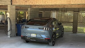 Ein Auto steht in einer Garage mit Betonboden und Holzbalkendecke.