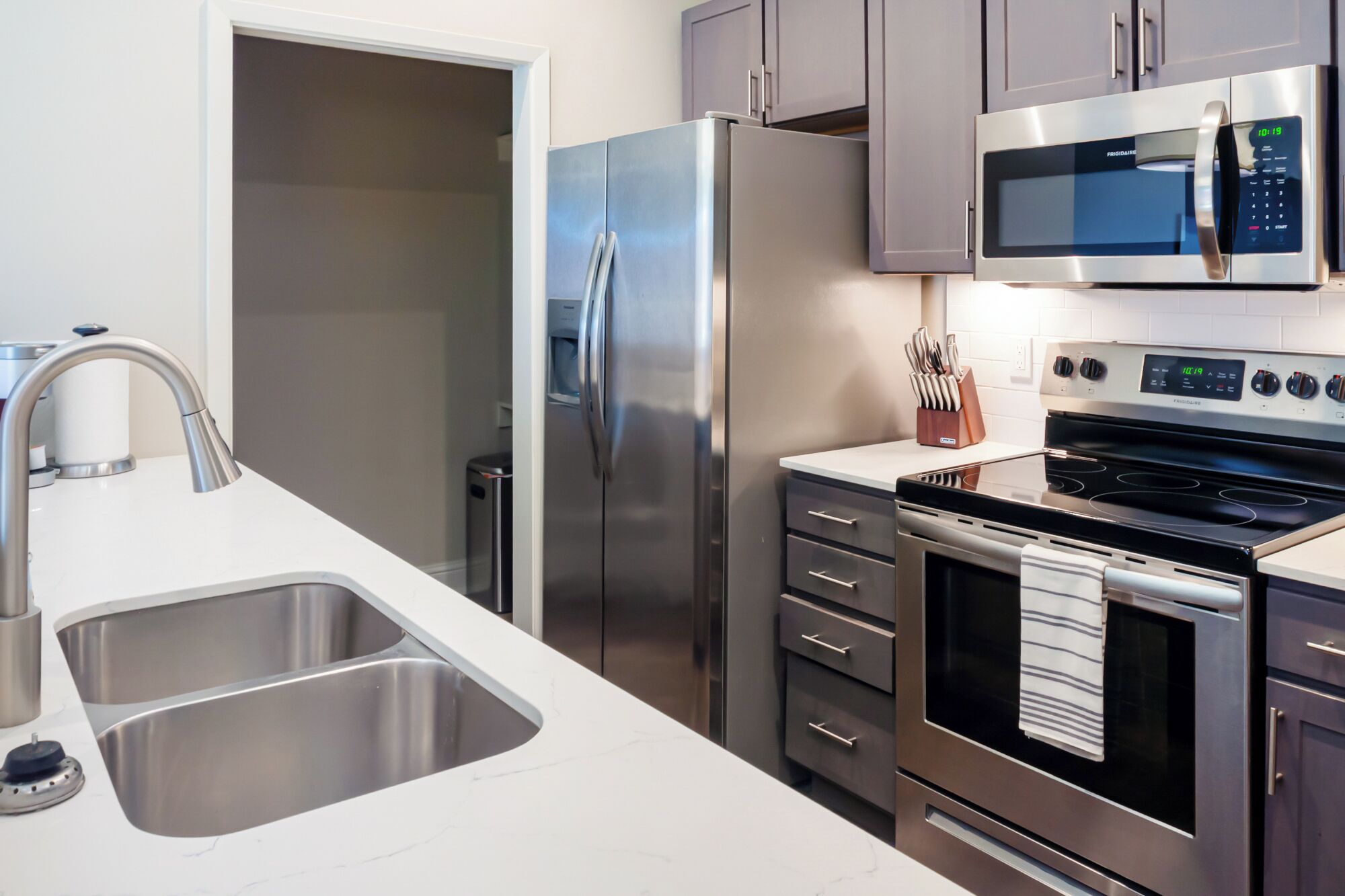 Una cocina moderna con electrodomésticos de acero inoxidable, incluyendo un refrigerador, microondas y horno.