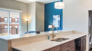 Une cuisine moderne dotée d’un grand îlot central, d’appareils électroménagers en acier inoxydable et d’un mur d’accent bleu.