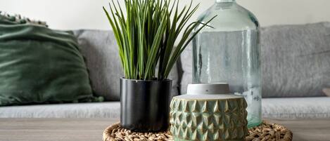 A woven placemat on a wooden table with a potted plant, a glass bottle, and a ceramic container.