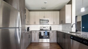Uma cozinha moderna com eletrodomésticos de aço inoxidável, armários de madeira e bancada de granito.