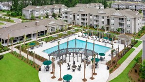 Complejo residencial con piscina central, zonas de estar al aire libre y terraza cubierta.
