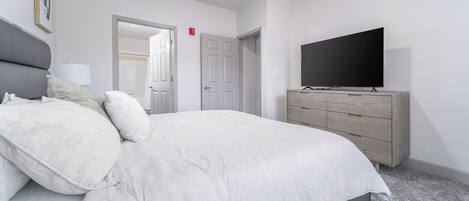 A bedroom with a bed, a dresser, a television, and a door.