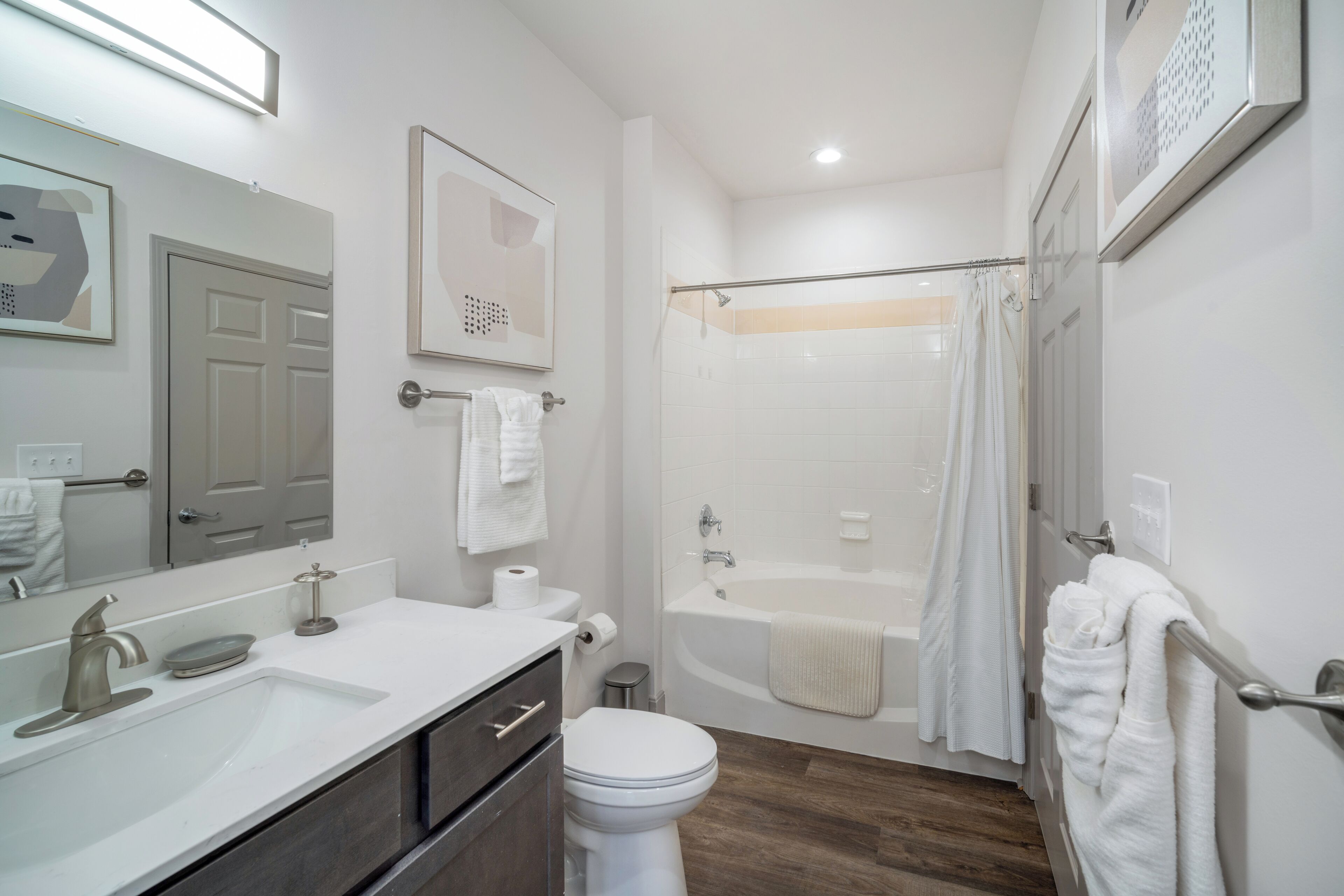 A modern bathroom with a sink, toilet, and bathtub.