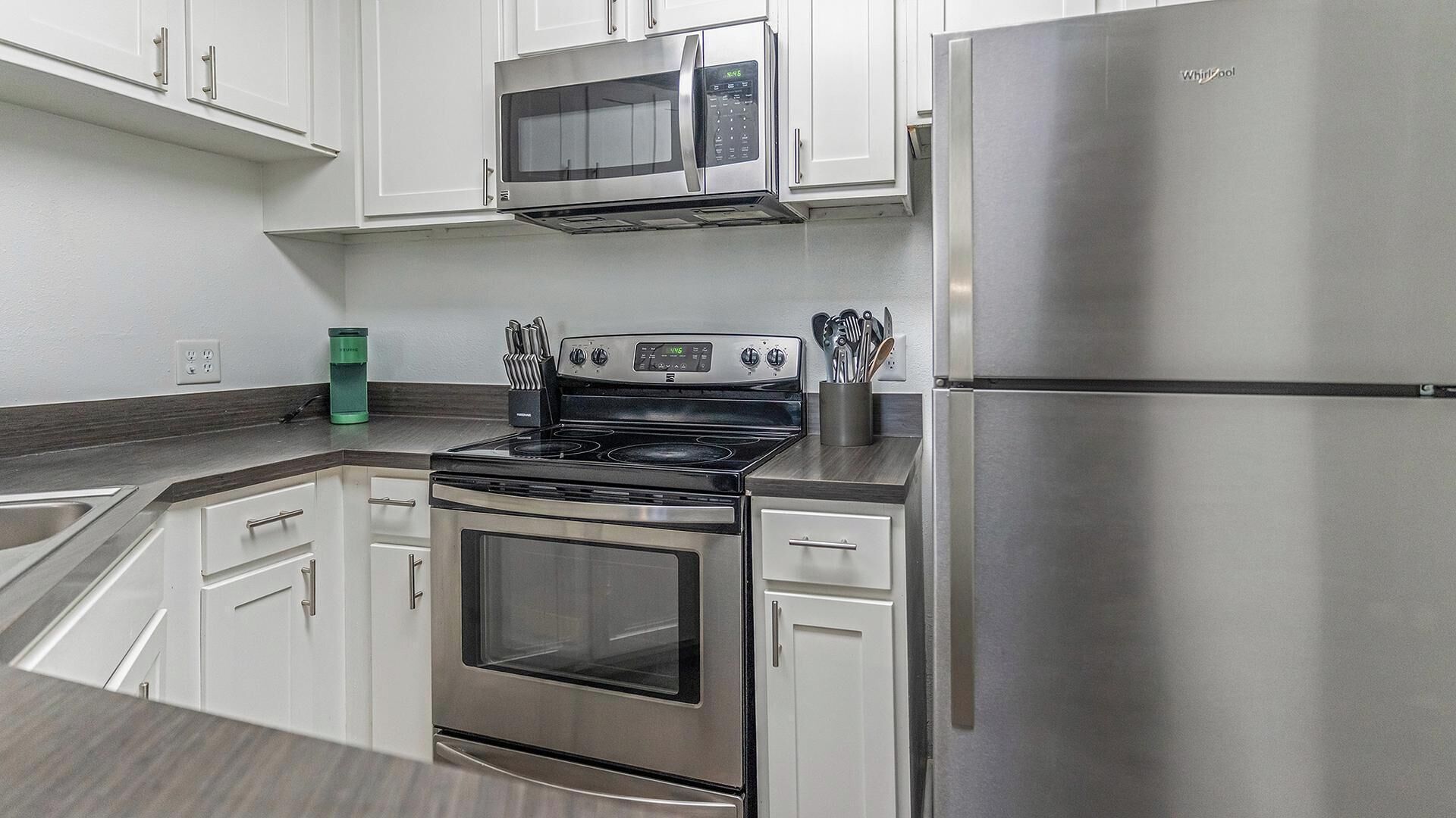 A modern kitchen with stainless steel appliances, including a microwave, oven, and refrigerator.