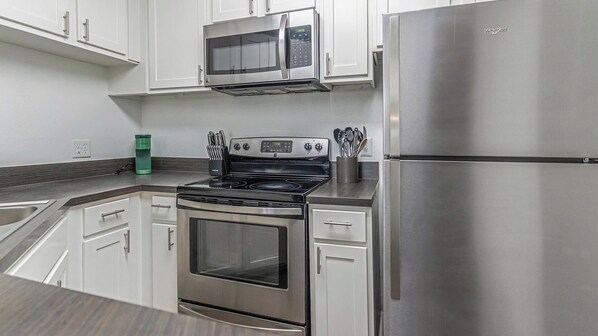 A modern kitchen with stainless steel appliances, including a microwave, oven, and refrigerator. - Landing Jacksonville (Jacksonville)