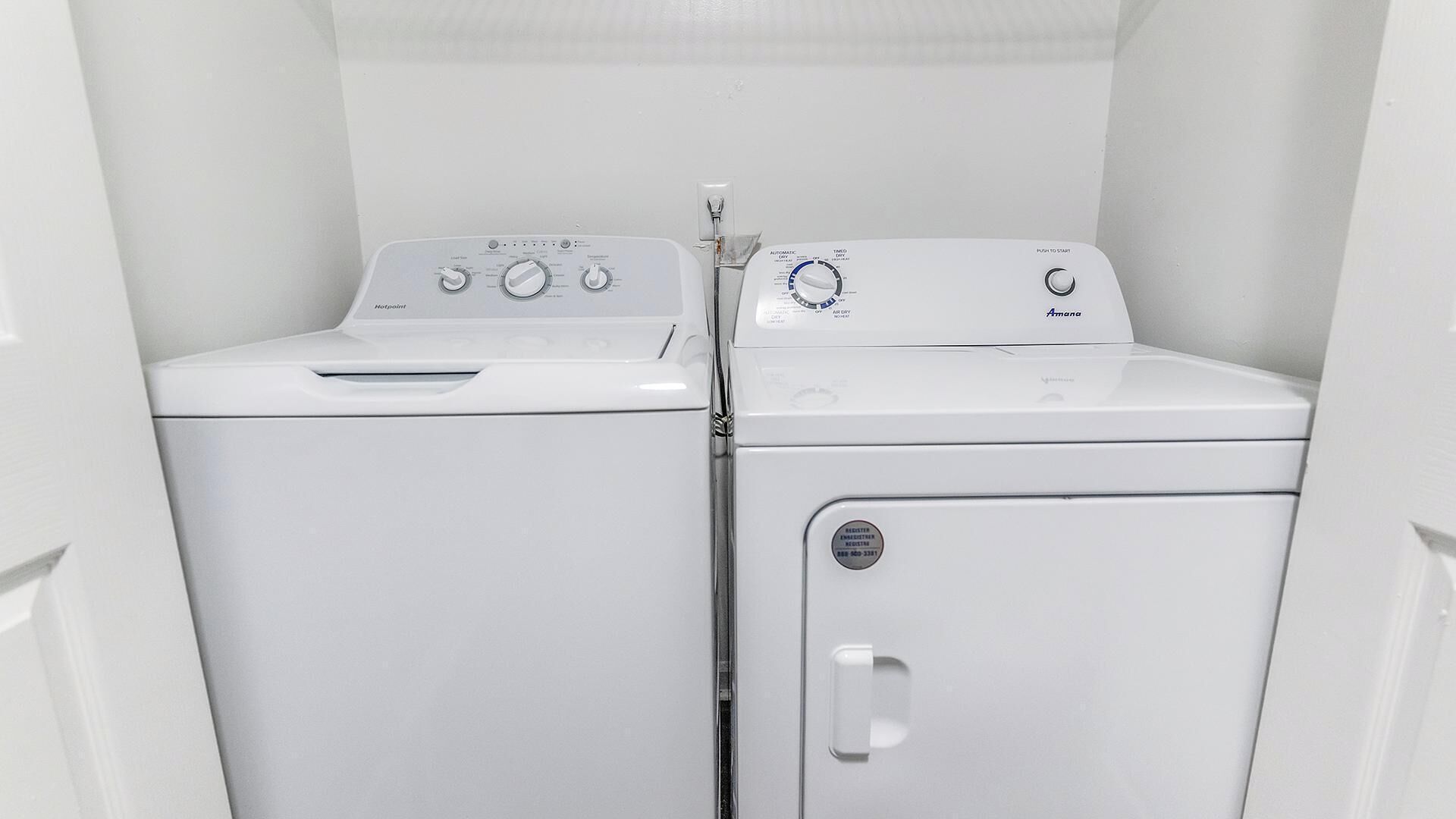 A laundry room with two white front-loading washing machines and a dryer.