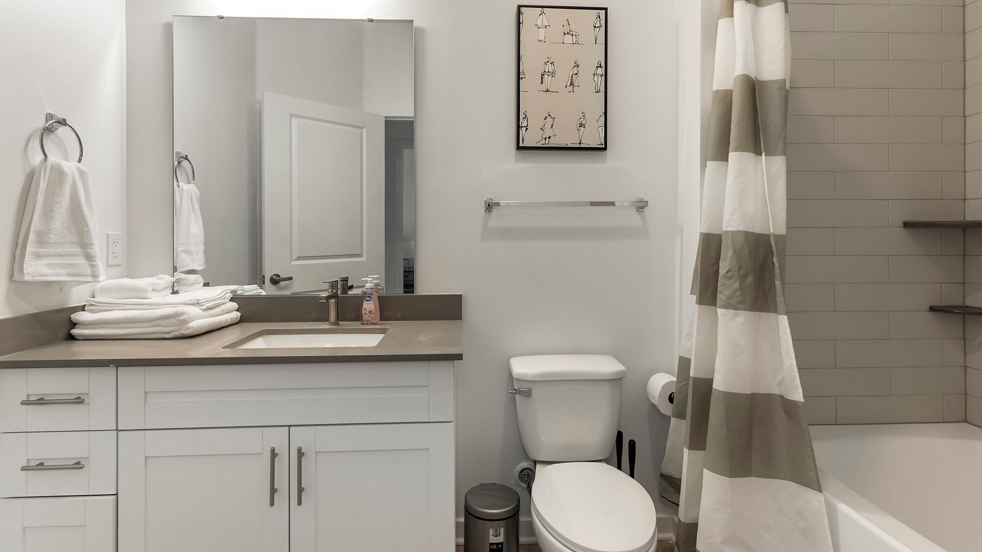 A modern bathroom with a sink, toilet, and shower curtain.