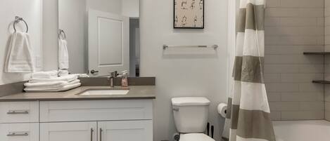 A modern bathroom with a sink, toilet, and shower curtain.