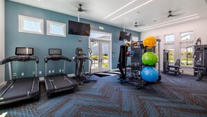 Un gimnasio con cintas de correr, máquinas de pesas y pelotas de ejercicio.