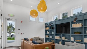 Una sala de estar moderna con un sofá modular, un sillón gris y una estantería llena de libros y objetos decorativos.