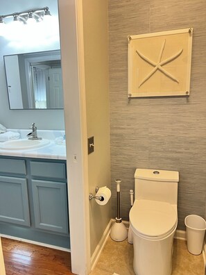 Een badkamer met toilet, wastafel en spiegel.