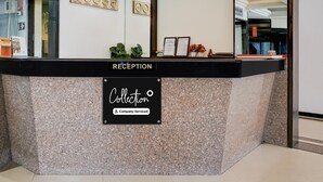 A reception desk with a sign indicating it's a company-serviced collection point. - Super Deluxe Twin Room Hotel Harmony (Rajkot)