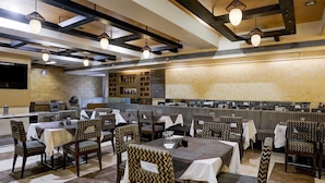 A restaurant with booths and tables, patterned chairs, and hanging pendant lights. - Super Deluxe Twin Room Hotel Harmony (Rajkot)