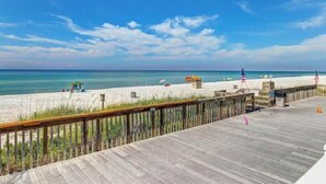 A wooden boardwalk leading to a sandy beach with a clear view of the ocean.