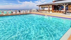 A clear blue pool with lounge chairs and a bar area.
