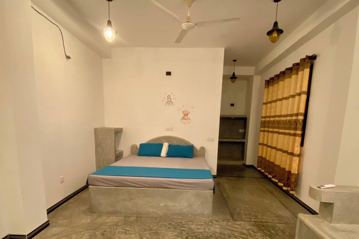 A bedroom with a bed, a ceiling fan, and a window with curtains.