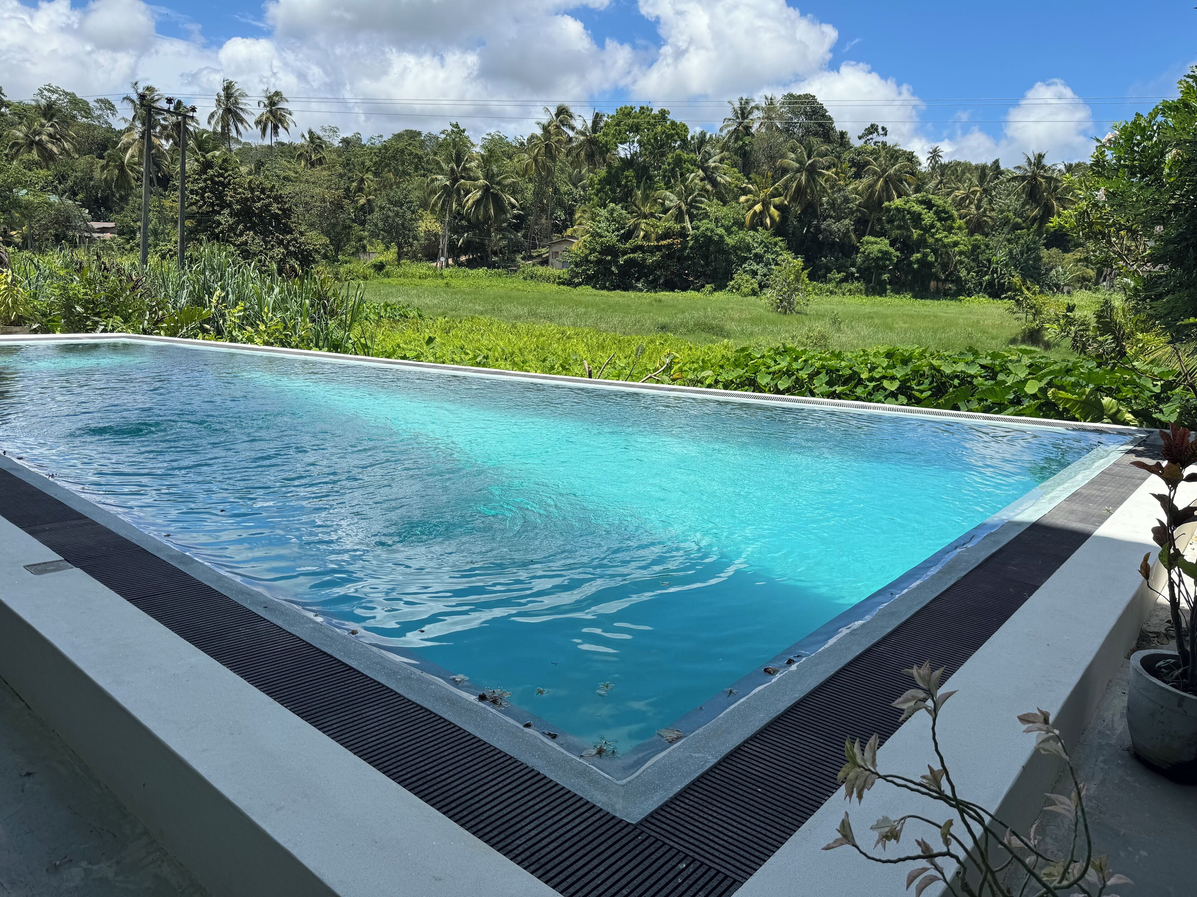 Una piscina rectangular con agua cristalina, rodeada por un deck de concreto y una barandilla metálica de seguridad.