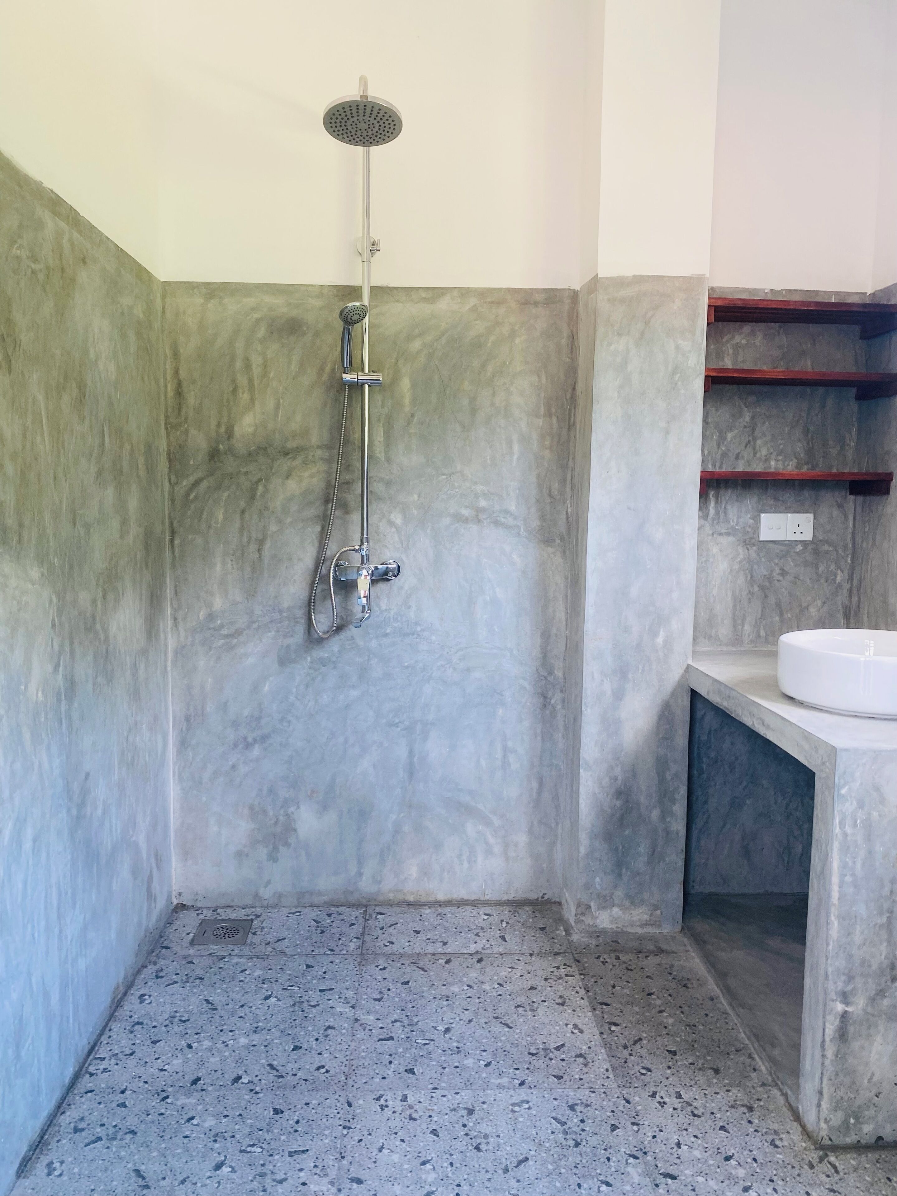 A bathroom with a shower, a sink, and a tiled floor.