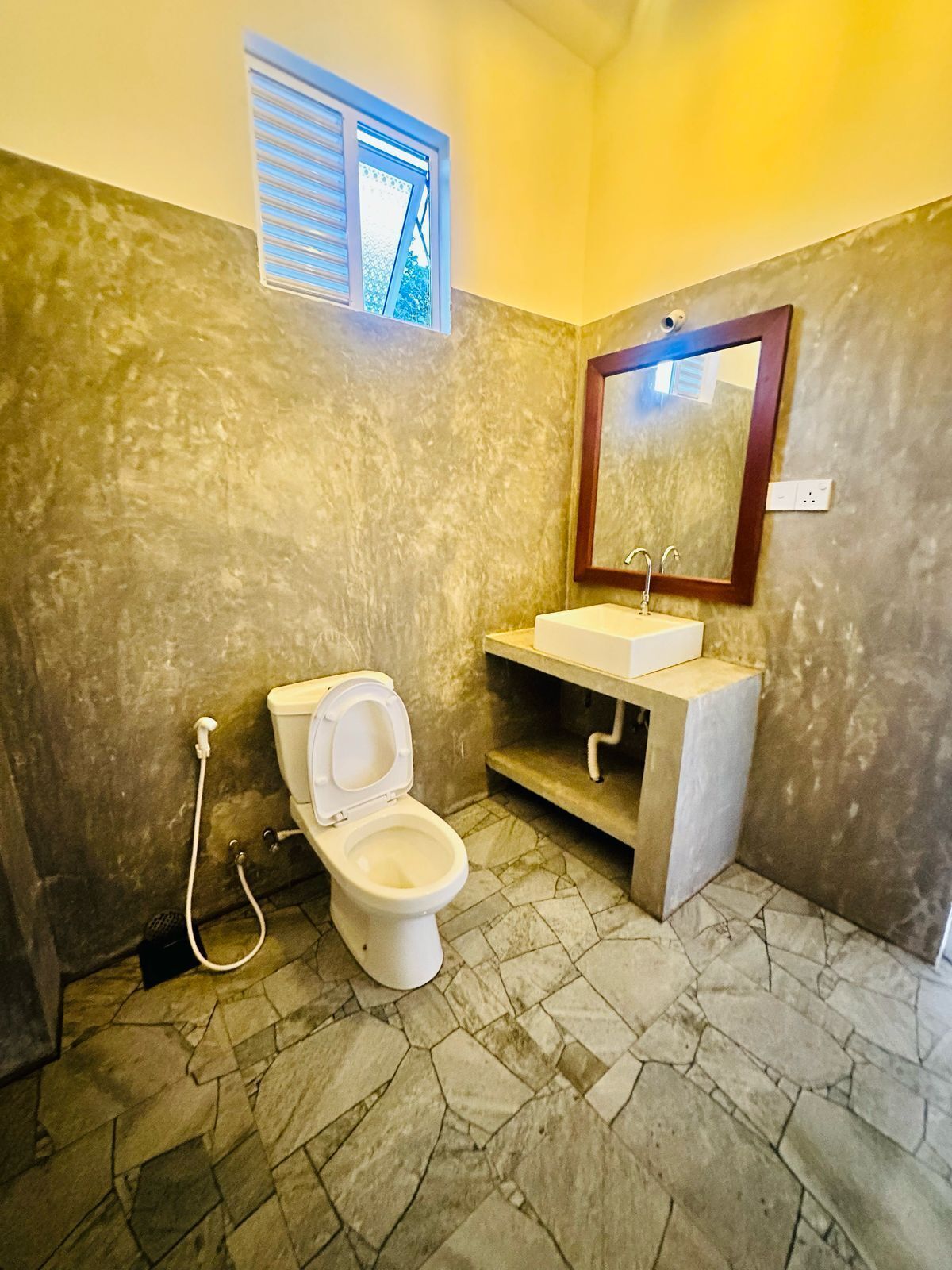 A bathroom with a toilet, sink, and mirror.