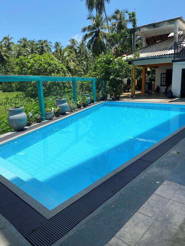 A rectangular swimming pool with a tiled edge, surrounded by a low teal fence. - southern grace hotel (Unawatuna)