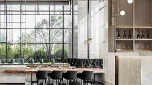 Una cocina moderna con un ventanal grande, un comedor con una mesa larga y sillas, y una estantería para vinos con botellas.