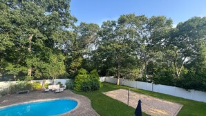 A backyard with a swimming pool, a brick patio, and a grassy lawn. - Hampton Gem: Heated Pool, BBQ, 5 Min to the Beach (Hampton Bays)