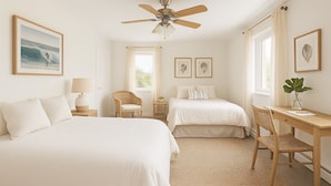 A bedroom with two beds, a desk, a chair, a ceiling fan, and framed artwork on the walls. - Hampton Gem: Heated Pool, BBQ, 5 Min to the Beach (Hampton Bays)