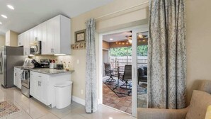 A modern kitchen with white cabinets, stainless steel appliances, and a dining area with a table and chairs.