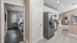 A modern kitchen with a stainless steel refrigerator, white cabinets, and a dining area with a table and chairs.