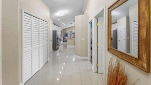 A corridor with white sliding doors, a large mirror, and a tiled floor.
