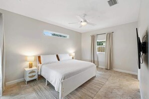 A bedroom with a bed, nightstands, a ceiling fan, and a window with curtains. - Heated Pool & Hot Tub | 4BR Sarasota Home – Pets OK (Sarasota)