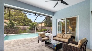 A patio with a pool, wicker furniture, and a ceiling fan. - Heated Pool & Hot Tub | 4BR Sarasota Home – Pets OK (Sarasota)