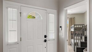 A white door with a small window, a keyhole, and a doorbell. - Heated Pool & Hot Tub | 4BR Sarasota Home – Pets OK (Sarasota)