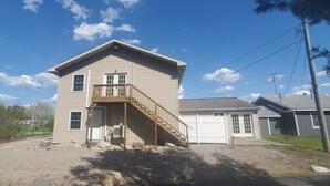 A two-story house with a front porch and a staircase leading to the second floor. - Large studio apartment in charming Elk Rapids. (Elk Rapids)