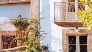 A traditional building with a tiled roof, a balcony with a wrought iron railing, and a stone facade. - Quintal do Grémio (Torre de Moncorvo)