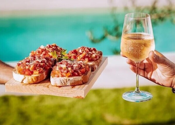 A wooden board with bruschetta and a glass of white wine. - Quintal do Grémio (Torre de Moncorvo)