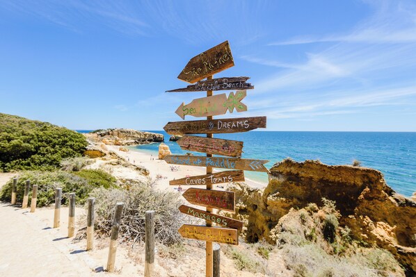 A wooden signpost with multiple directional arrows pointing to various attractions such as "Sea Food," "Dreams," and "Caves Tours."