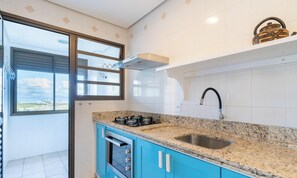 Een moderne keuken met een gasfornuis, een roestvrijstalen spoelbak en blauwe kastjes.