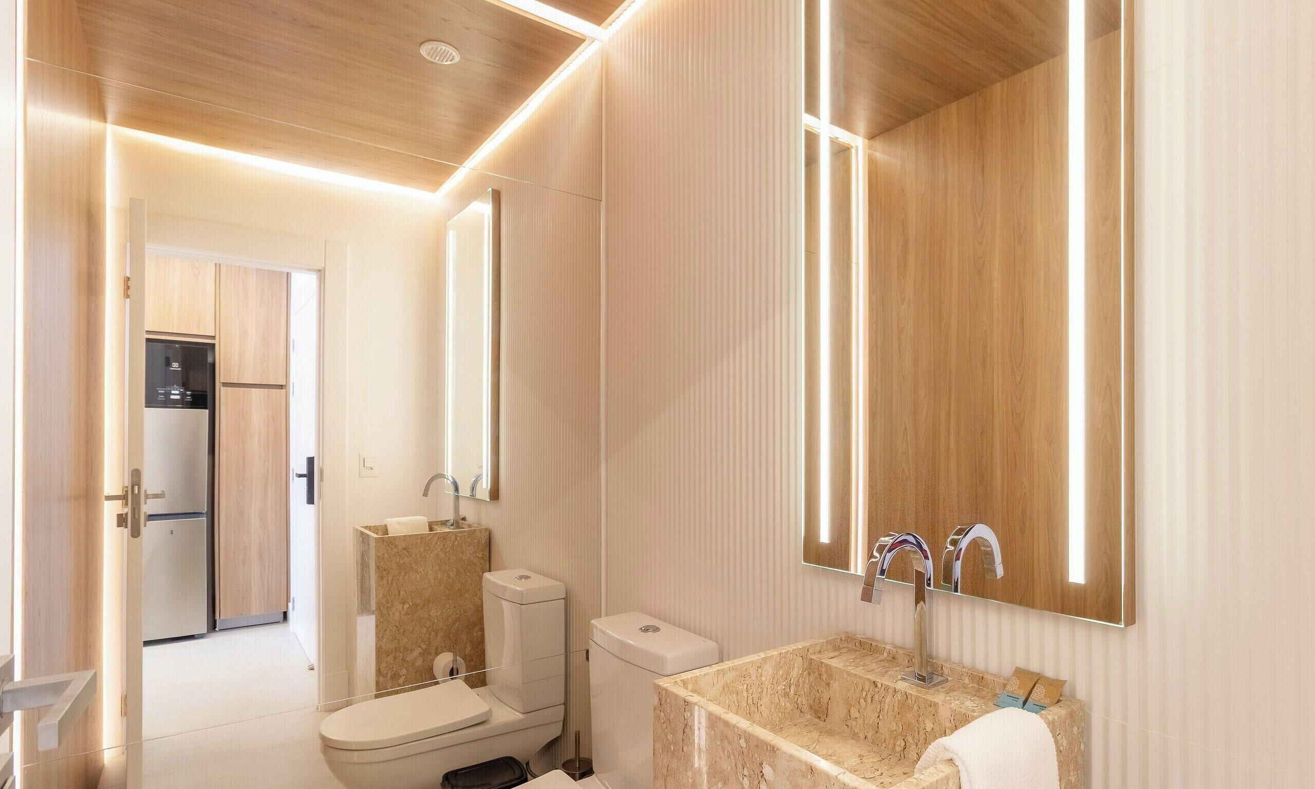 A modern bathroom with a toilet, sink, and mirror.