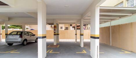 A covered parking area with columns and yellow directional arrows on the floor.