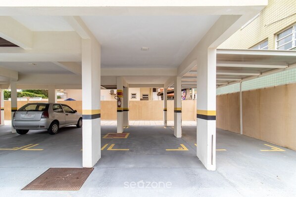 Un área de estacionamiento techada con columnas y flechas direccionales amarillas en el suelo.