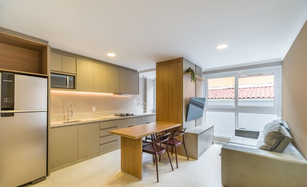 A modern kitchen with a dining area, built-in appliances, and a large window.