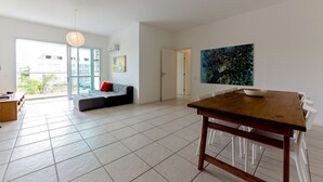 A spacious living area with a dining table, a sofa, and a large window.